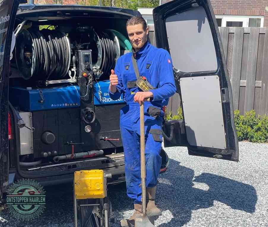 Een tevreden monteur met opgestoken duim naast de bestelbus, slim ingrijpen bespaart kosten bij een verstopte afvoer in Haarlem