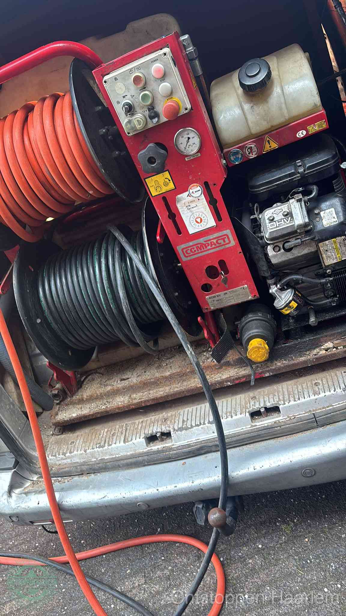Een rood hogedruk-rioolreinigingstoestel in de laadbak van de bedrijfsbus, apparatuur voor een hardnekkige afvoerverstopping in Haarlem