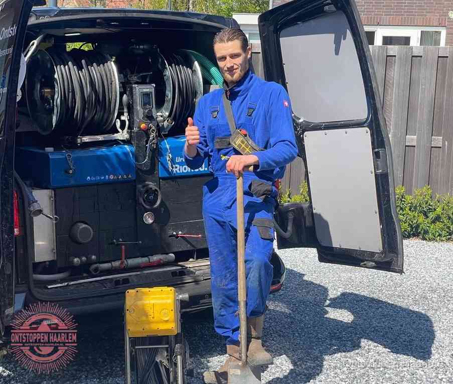 Een monteur bij de werkbus met grote hogedruk-slanghaspels, apparatuur voor hardnekkige afvoerverstoppingen in Haarlem