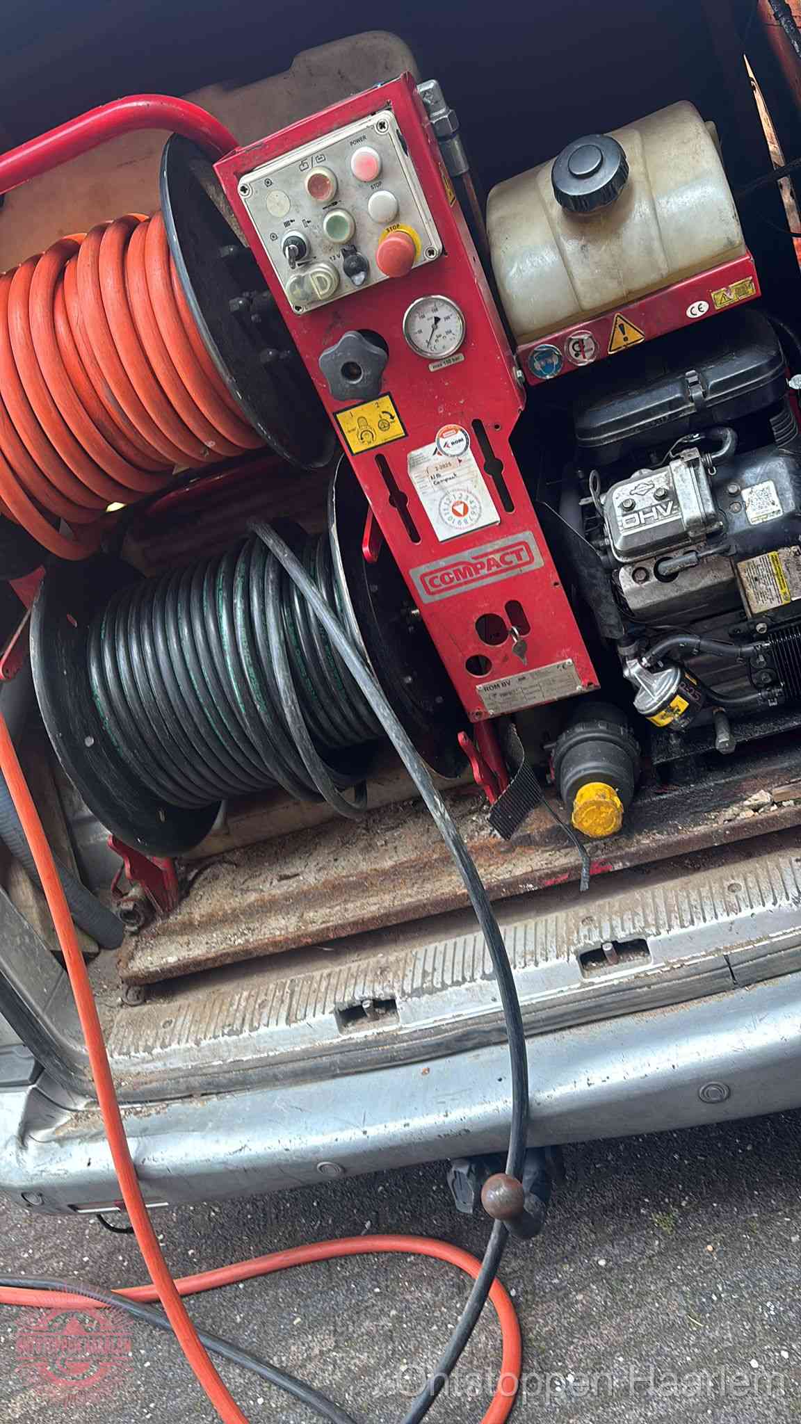 Een rood hogedruk-rioolreinigingstoestel met slangen in de laadbak van de bedrijfsbus, apparatuur voor een hardnekkige wc-verstopping in Haarlem