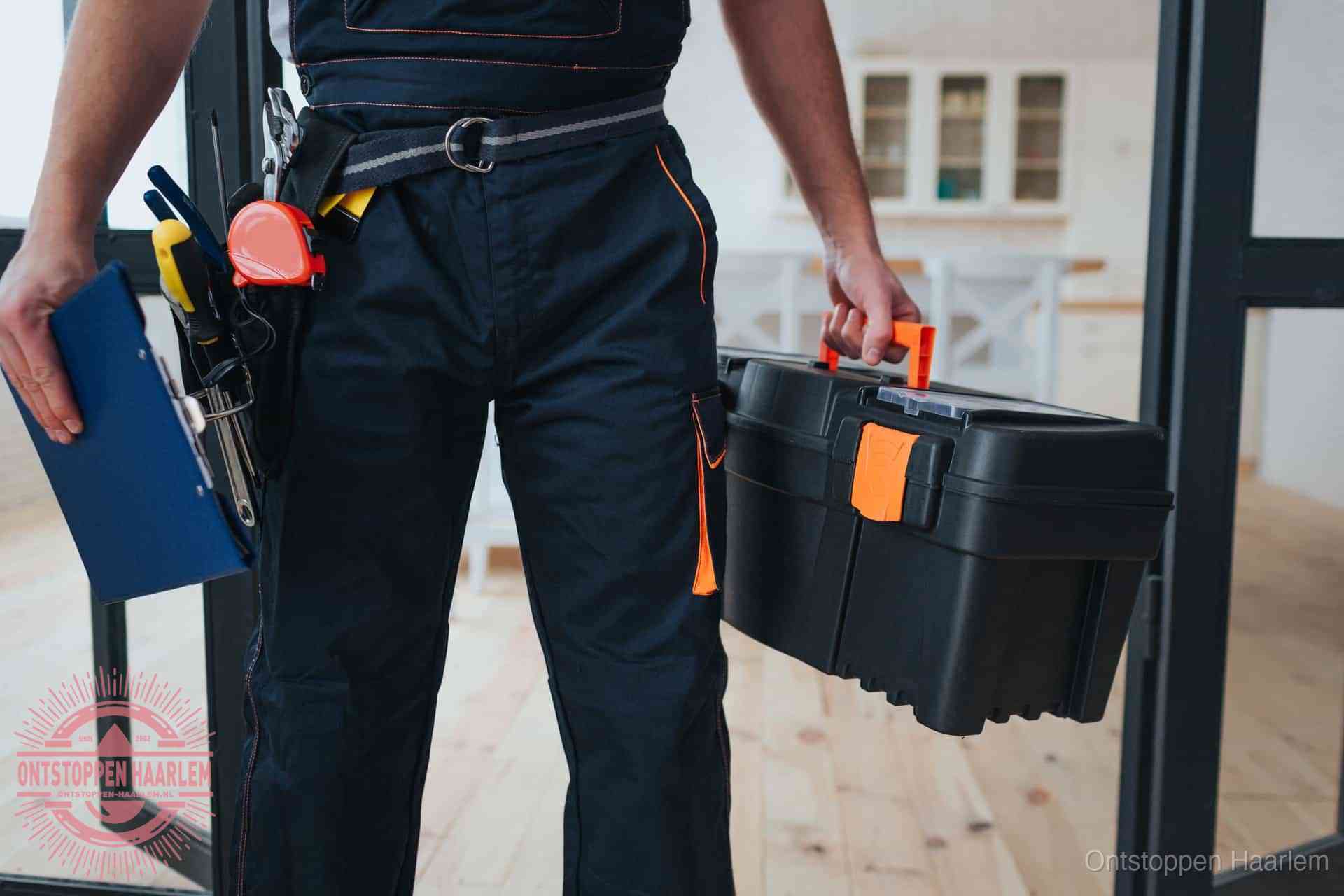 Een monteur met gereedschapsriem en klembord in een keuken, klaar om een transparante prijs voor het gootsteen ontstoppen in Haarlem te geven