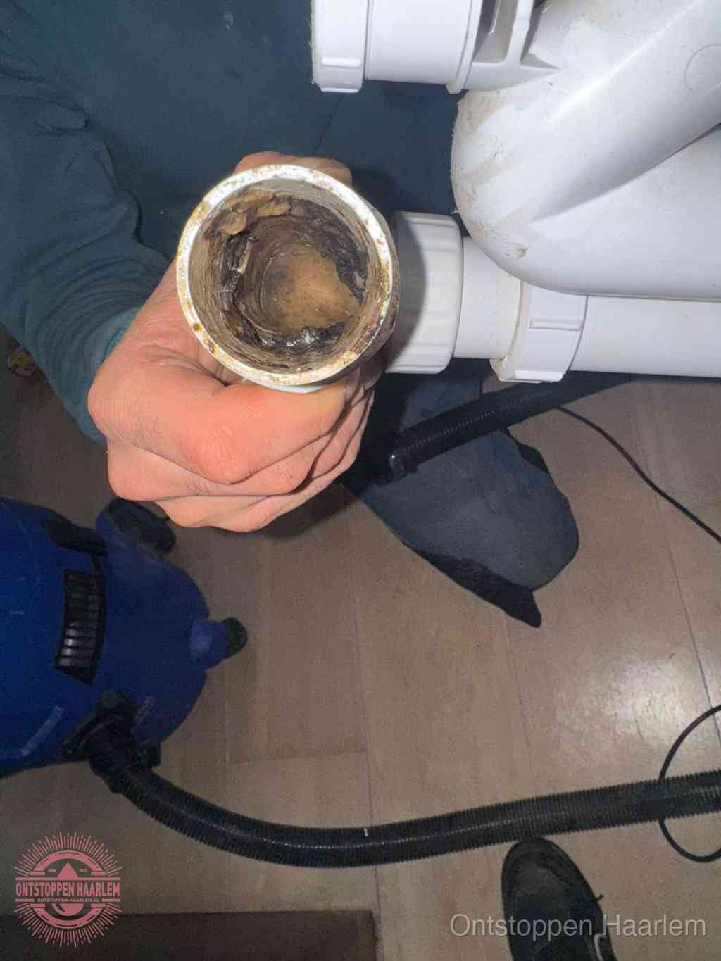 Een losgekoppelde afvoerbuis die van binnen volledig is dichtgeslibd met vet en aanslag, de meest voorkomende oorzaak van een verstopte gootsteen in Haarlem