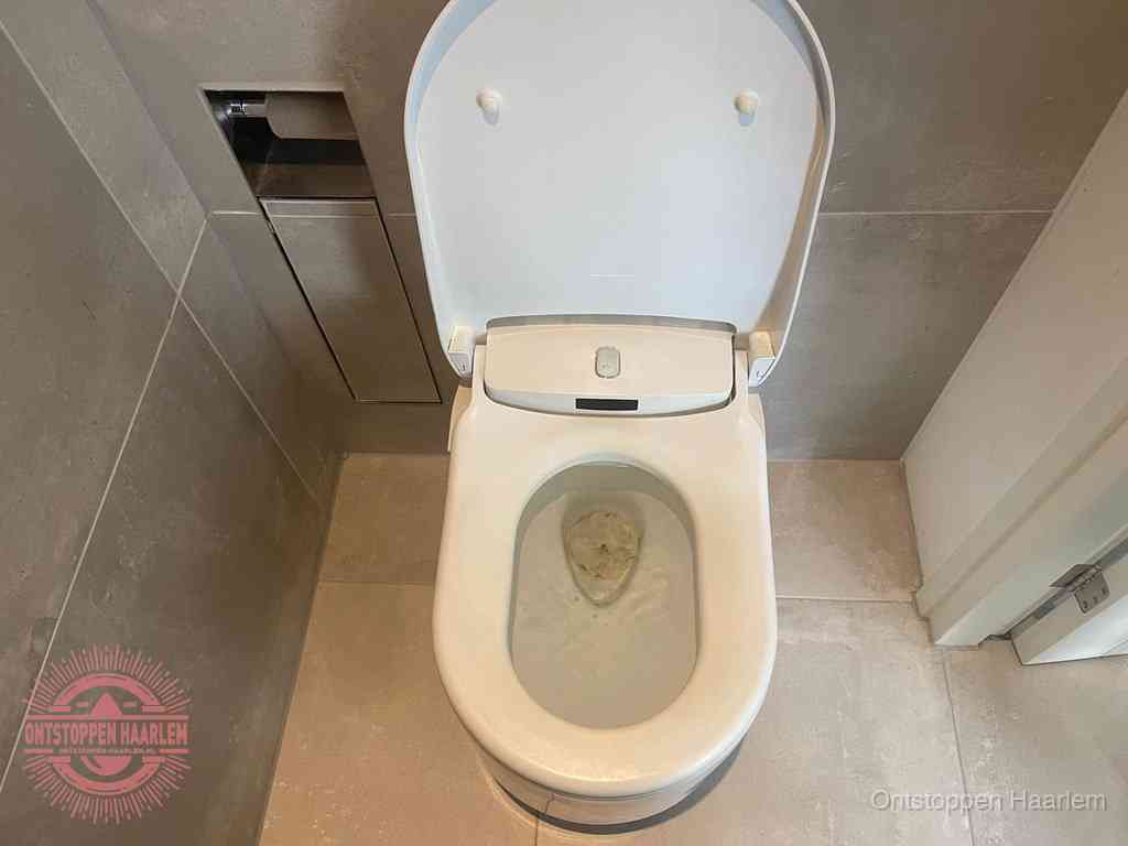Een wit hangtoilet waarin een prop wc-papier op het water blijft drijven, een duidelijk signaal van een verstopte wc in Haarlem