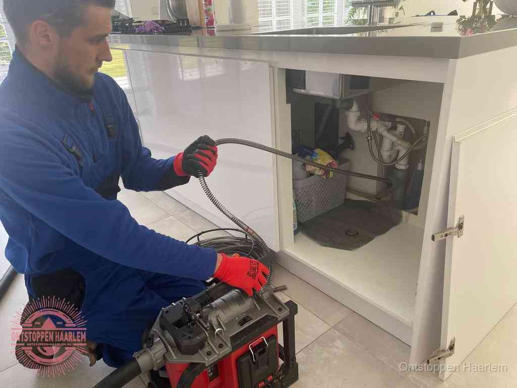 Een monteur reinigt de keukenafvoer grondig met een veermachine om terugkerende gootsteenverstoppingen te voorkomen in Haarlem