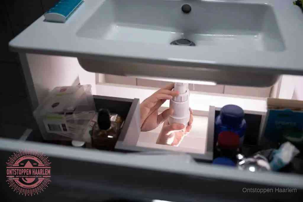 Een pompfles met zeep boven een wastafel in de toiletruimte, de warm water en afwasmiddel-methode om de wc te ontstoppen in Haarlem