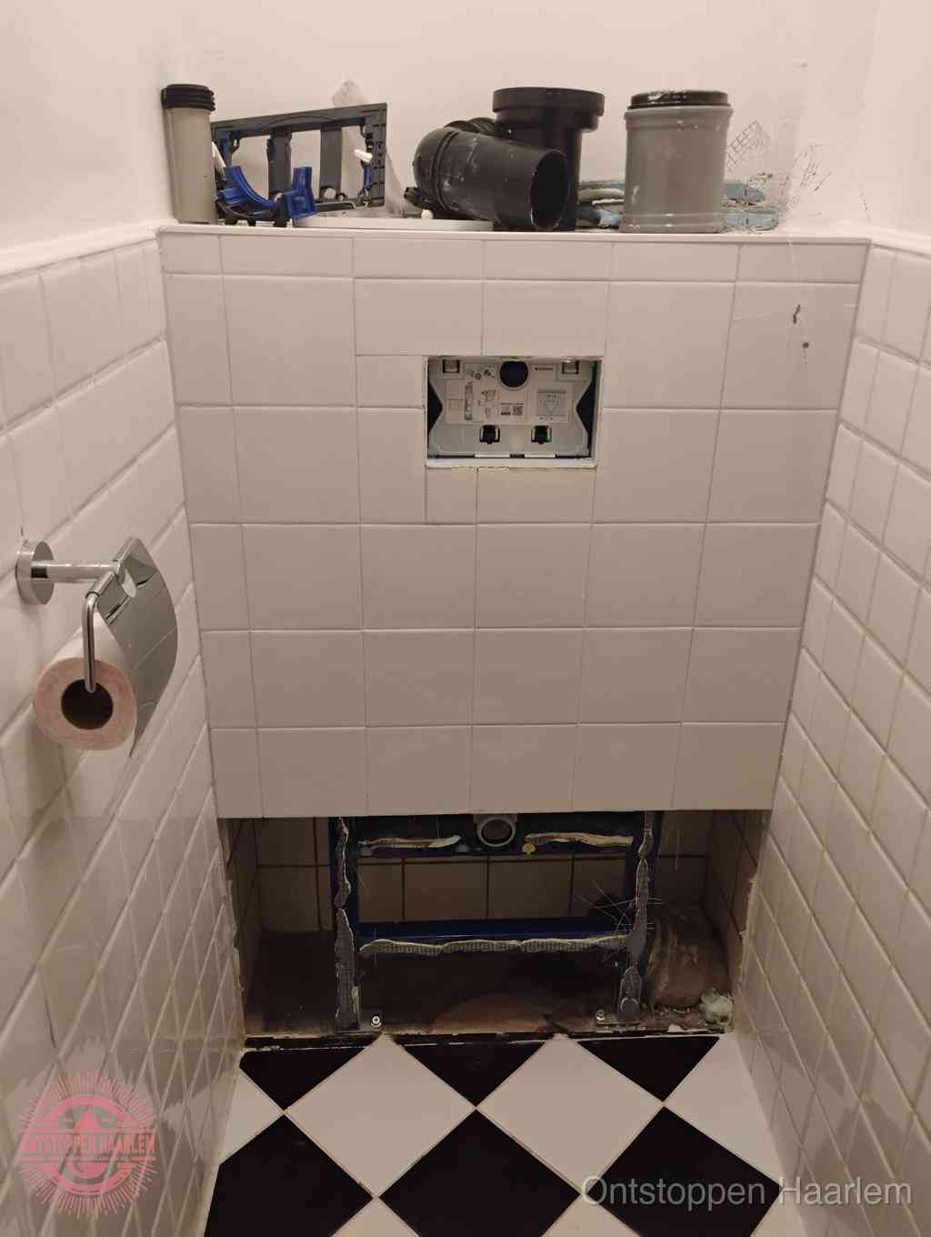 Een toiletruimte waar het hangtoilet en de inbouwreservoir-onderdelen zijn vrijgelegd voor onderhoud, periodiek nazicht voorkomt een wc-verstopping in Haarlem