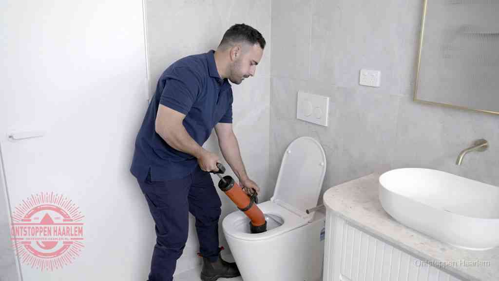 Een monteur gebruikt een handmatige perspomp (toiletontstopper) op een wandcloset tijdens het professioneel wc ontstoppen in Haarlem